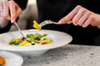 © pavel siamionov - A close-up of hands using a fork and knife to enjoy a fresh salad, featuring colorful vegetables and greens, highlighting the dining experience in a cozy setting.