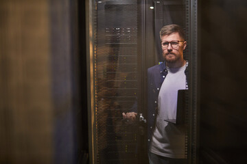 Poster - Portrait of man in a modern server room inspecting servers with focus on technology and equipment working environment without any unnecessary details