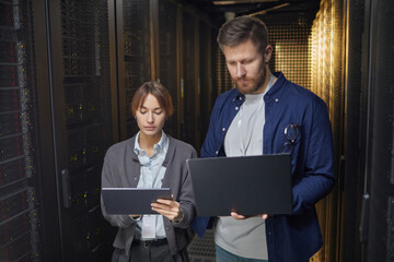Poster - Two IT professionals working together in a data center, using tablets to monitor servers and network equipment creating an efficient and organized environment