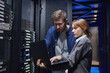 © Seventyfour - Two IT professionals are examining server connections in a data center, focusing on laptop screen while discussing necessary steps for troubleshooting issues