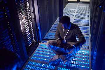 Poster - Engineer working in a high-tech server room, managing data servers and ensuring smooth operation of systems. Blue lighting adding to the futuristic atmosphere
