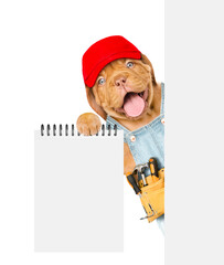 Poster - Happy Mastiff puppy wearing red cap and denim overalls with tool belt shows empty list from behind blank white banner. Isolated on white background
