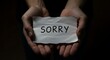 © mhmdyatt - Hands Holding Paper Saying Sorry Offering Apology in Dark Lighting