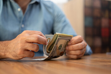 Aufkleber - Male entrepreneur holds pack of dollar banknotes in hands carefully counting money for future investment project sitting at workplace in company office