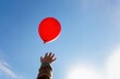 © Volha - child reaching towards red balloon in blue sky, symbolizing freedom, childhood dreams, letting go, hope, or change. ideal image for concepts related to joy, aspiration, imagination
