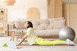 © Pixel-Shot - Beautiful young woman with laptop practicing yoga on mat in living room