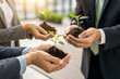 © yousaf - Business Growth and Sustainability Concept with Team Holding Seedlings