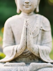 Poster - Elegant Buddhist Statue with Hands in Prayer Pose Against a Green Natural Background : Generative AI