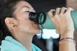 © 2B - Woman exercising in outdoor gym while taking a break to hydrate on a sunny day