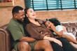 © chokniti - Heartwarming family moment as an African American father and daughter share playful time together on the couch, surrounded by love, laughter, and the warmth of home, while mom gently looks on with joy