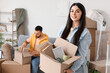 © Pixel-Shot - Happy young woman with box and her husband packing belongings in room on moving day