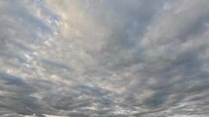 Wall Mural - Beautiful white with pink tint clouds moving fast across the sky at dawn under blue sky on sunny day. Time lapse mode.