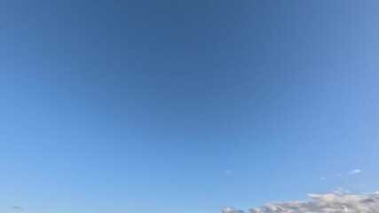 Wall Mural - Beautiful white with pink tint clouds moving fast across the sky at dawn under blue sky on sunny day. Time lapse mode.