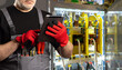 © Grispb - Electrician in work gloves uses a tablet to inspect and monitor an open electrical panel with wiring and components. - Electrical maintenance, Power systems.