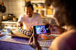 © Marko Geber - Woman taking photo of gourmet sushi plate while chef finishes presentation in restaurant kitchen