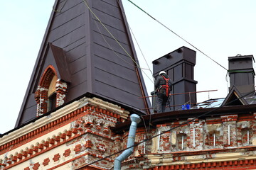 Poster - A person stands on the rooftop next to a clock tower, providing a sense of perspective and scale.