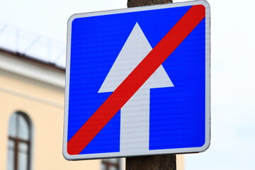 Aufkleber - A blue and red street sign on a pole in the city.