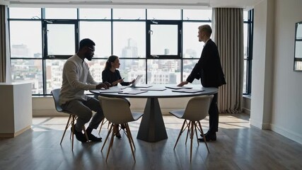 Aufkleber - Diverse team of business professionals collaborates around a circular table in a modern office space with panoramic city views, reviewing documents and engaging in productive discussion