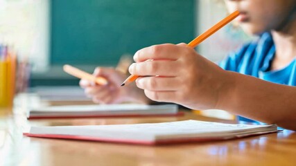 Aufkleber - Elementary school student carefully practicing writing on notebook with orange pencil in slow motion, improving handwriting and focusing on task during class
