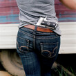 © RooM The Agency - Close-up rear view of a woman with a handgun tucked into the back of her jeans