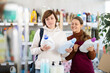 © JackF - Girl consultant helps woman buyer choose rinsing gel, answers questions and accompanies during shopping. Employee recommends that buyer pay attention to item from well-known manufacturer