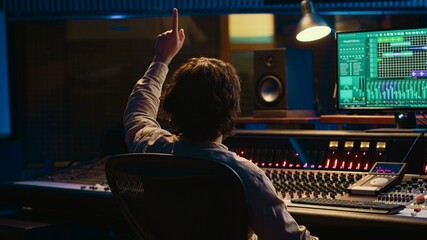 Leinwandbilder - Sound engineer counting down for artist in vocal booth to start singing and producing new music, control room technical gear. Skilled audio technician operating knobs and sliders. Camera A.