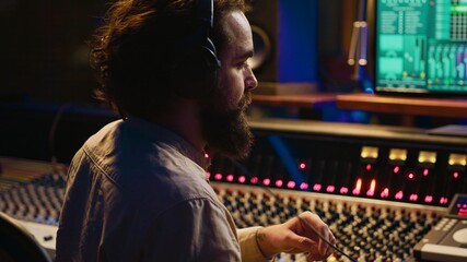 Leinwandbilder - Mixing engineer pressing sliders on control desk to balance tracks and add sound effects, creating new music. Audio engineering expert works with motorized faders in professional studio. Camera A.