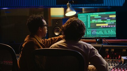 Leinwandbilder - Team of sound engineers working on recording and editing tracks in professional studio control room, collaborating on mix and master audio files. Musician and technician pressing sliders. Camera A.