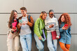 © Jose Calsina - Group of cheerful teens using their smartphones while enjoying together, sharing on the social media as they communicate through various applications and features on their mobile phone