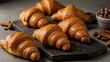 © Henhen - Freshly baked, golden brown croissants arranged on a dark wooden board with scattered coffee beans and cinnamon sticks. Perfect for a delightful breakfast or snack.