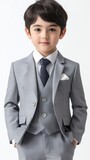 A young boy in a stylish light gray suit and tie.