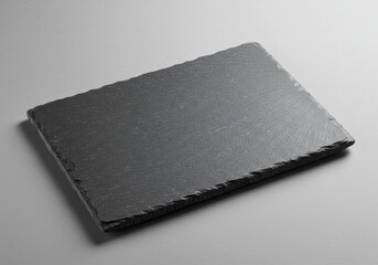 Poster - A close up shot of a rectangular dark gray slate plate on a gray surface with a subtle light source