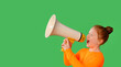 © Iryna - Child enthusiastically shouting through a megaphone against a vibrant green background in a playful indoor setting during a lively performance or announcement