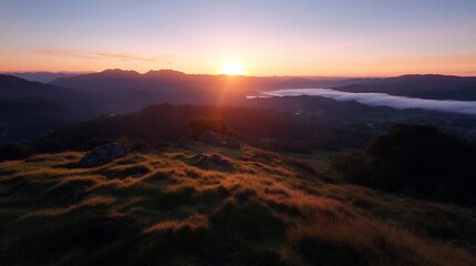 Poster - A serene sunrise illuminates a rolling landscape featuring hills, valleys and distant structures. Golden light bathes the scene emphasizing textures and shadows. Misty conditions enhancing depth and