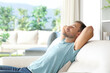 © Antonioguillem - Man relaxing sitting on a couch beside a window with nature views