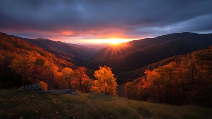 Leinwandbilder - Vibrant autumn landscape featuring a mountain range bathed in the warm glow of sunset with golden foliage and dramatic sky