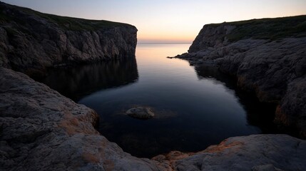 Poster - A scenic coastal landscape at dusk features a calm body of water framed by rocky cliffs with subtle vegetation illuminated by soft ambient light creating a tranquil atmosphere