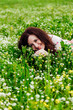 © dmitriisimakov - brunette woman lying in a field with flowers in spring and smiling