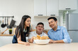 © Kawee - Asian happy family, mature parent having breakfast with son in kitchen.