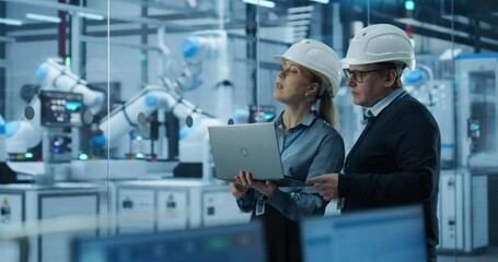 Leinwandbilder - Male Engineer and Female Project Manager Standing Next to an Assembly Line, Talking, Using Computer and Monitoring Production at a Modern Automated Electronics Manufacture with AI Robotic Arms