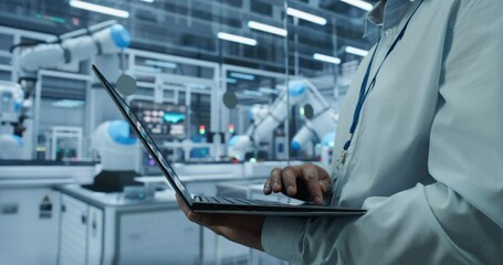 Fototapete - Anonymous Engineer Working in an Industrial Facility, Using Laptop to Monitor Robotic Arms in a Futuristic Electronics Production Factory. Close Up Footage with Focus on Computer