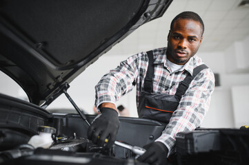 Poster - Engineer expertly examines car motor using advanced mechanical tools, ensuring optimal automotive performance and safety. African american garage employee conducts annual vehicle checkup