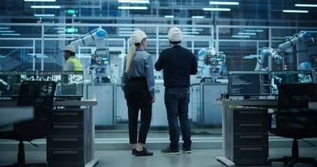 Leinwandbilder - Female and Male Industrial Engineers Having a Conversation at a Modern Tech Electronics Factory with Automated Robot Arms Working with the Help of Artificial Intelligence Software. Back View