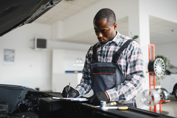 Poster - African man standing in a car repair shop