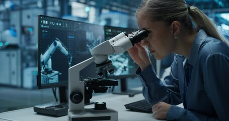 Leinwandbilder - Female Engineer Sitting Behind a Desk in an Electronics Manufacturing Facility, Inspecting High Tech Equipment Under a Microscope and Using Desktop Computer with Dual Screens to Optimize Production