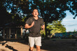 © Mdv Edwards - Middle aged Southeast Asian man runs through park wearing weighted backpack, captured mid-stride during an intense rucking workout.