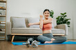 © Nuttapong punna - Asian Woman Doing Yoga and Watching Online Tutorials on Laptop, Training in Living Room