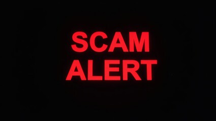 Poster - Illuminated red text reading 'SCAM ALERT' on a dark background, conveying a warning message.