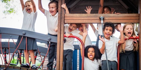 Poster - Group of diverse children playing on a playground, smiling and waving. Kids enjoying outdoor fun, diverse group, playground excitement, happy children. Diverse school kids at playground.