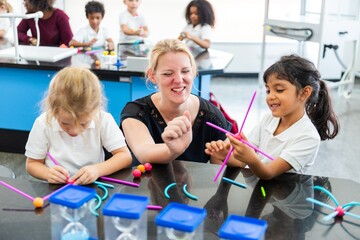 Poster - Teacher with diverse children in a classroom, in a STEM activity. Kids and teacher enjoying STEM learning with colorful materials in a lively classroom. Teacher working with elementary school children